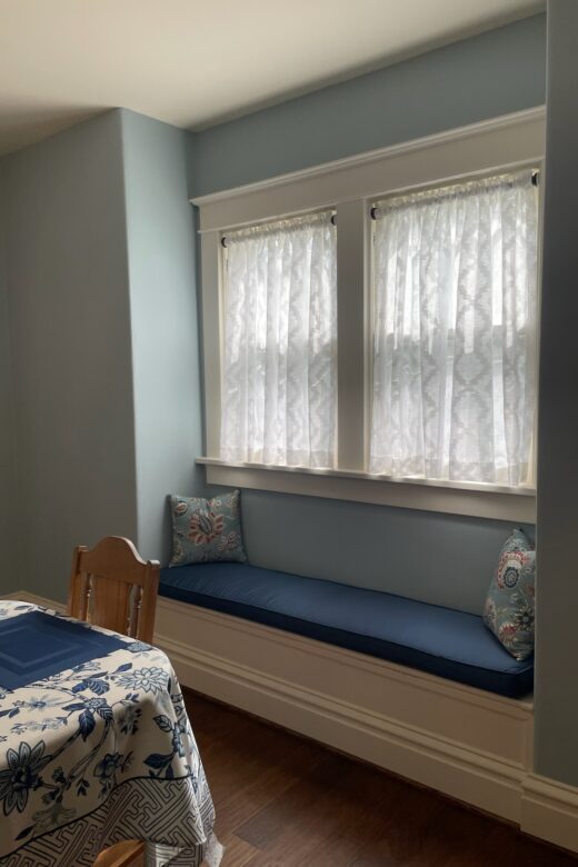Wide view of a dining room featuring custom soft window treatments that complement the home's traditional design.